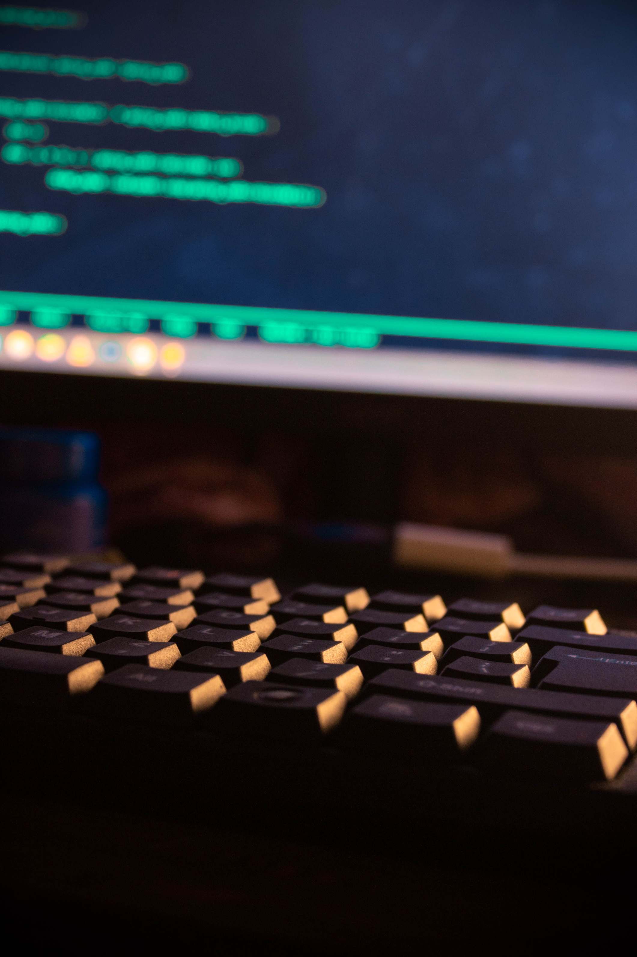 Close view of a workstation with monitor and keyboard, computer keyboard and monitor displaying code